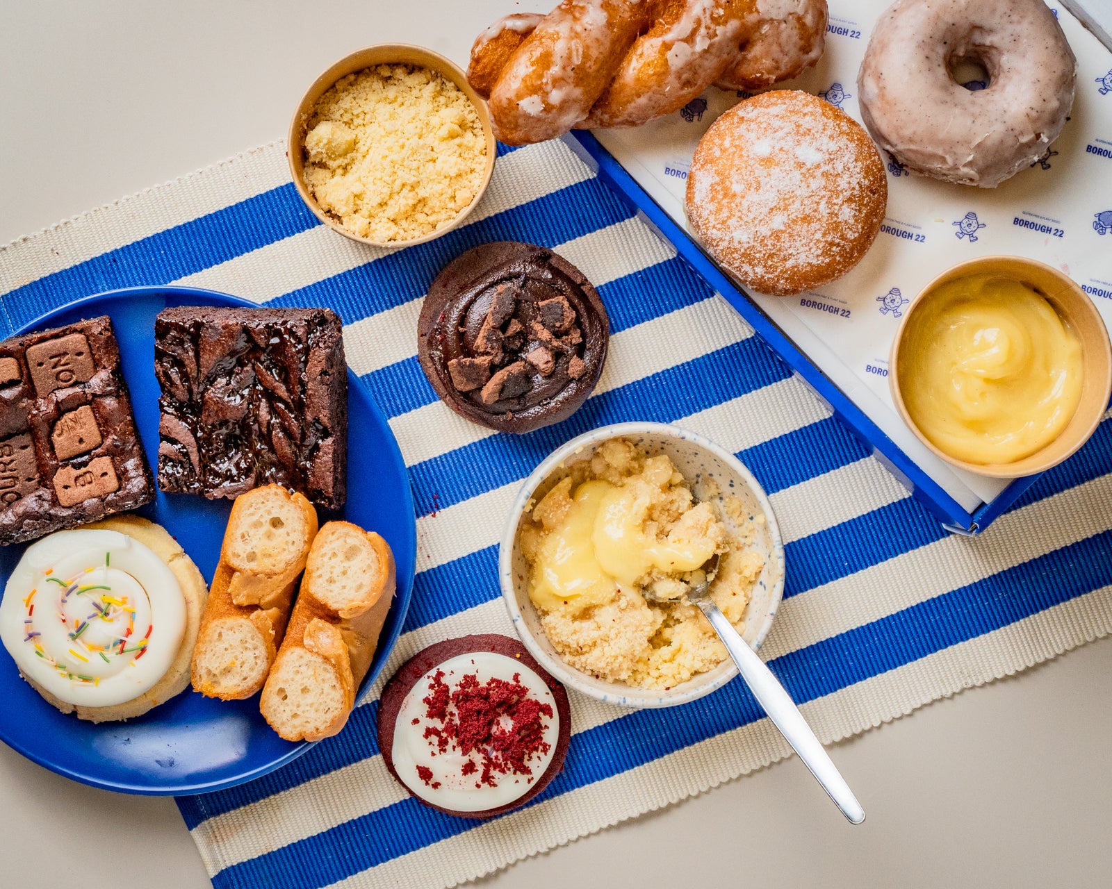 An overhead flat-lay of assorted baked and fried gluten free and vegan goods and desserts.