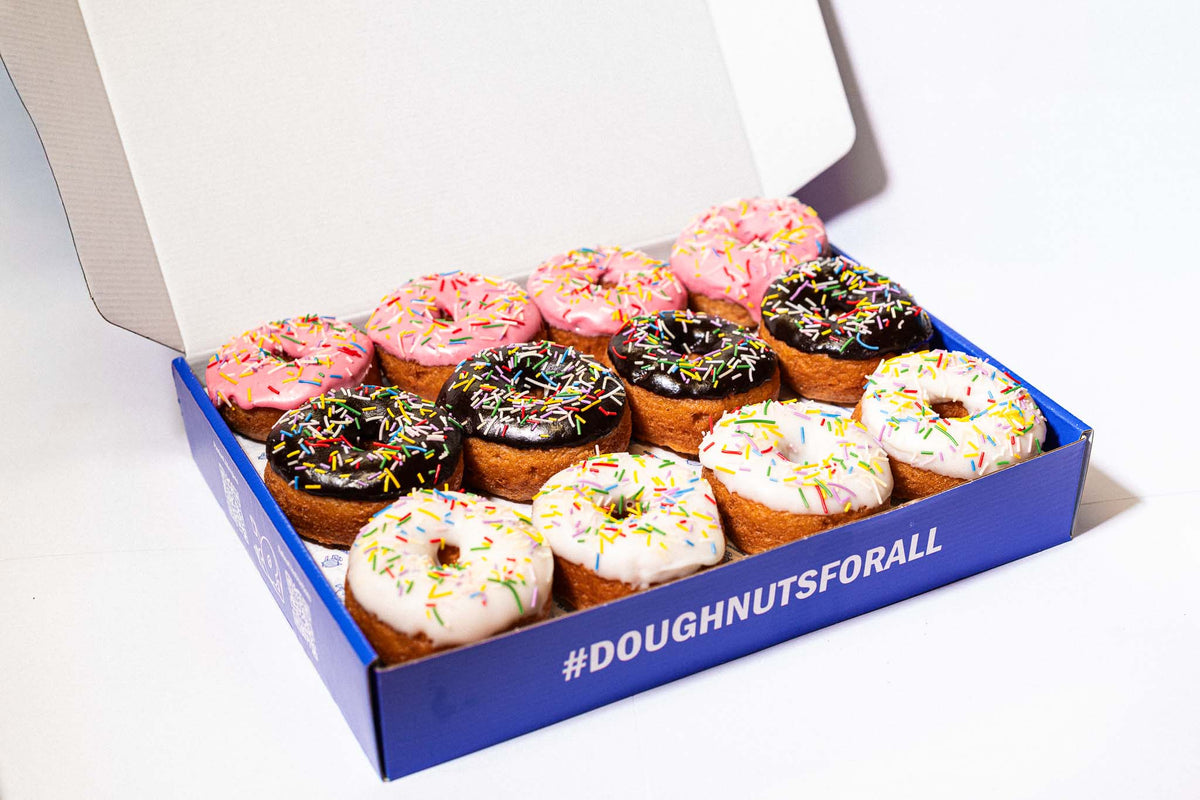 Box of assorted doughnuts with colorful glazes on a white background