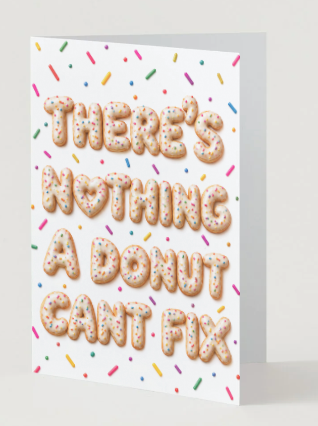A white greeting card with the phrase 'THERE'S NOTHING A DONUT CAN'T FIX' in raised donut-shaped letters with colorful sprinkles, shown standing against a light gray background.