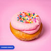 Gluten free vegan baked strawberry doughnut, pink strawberry icing covered in rainbow sprinkles