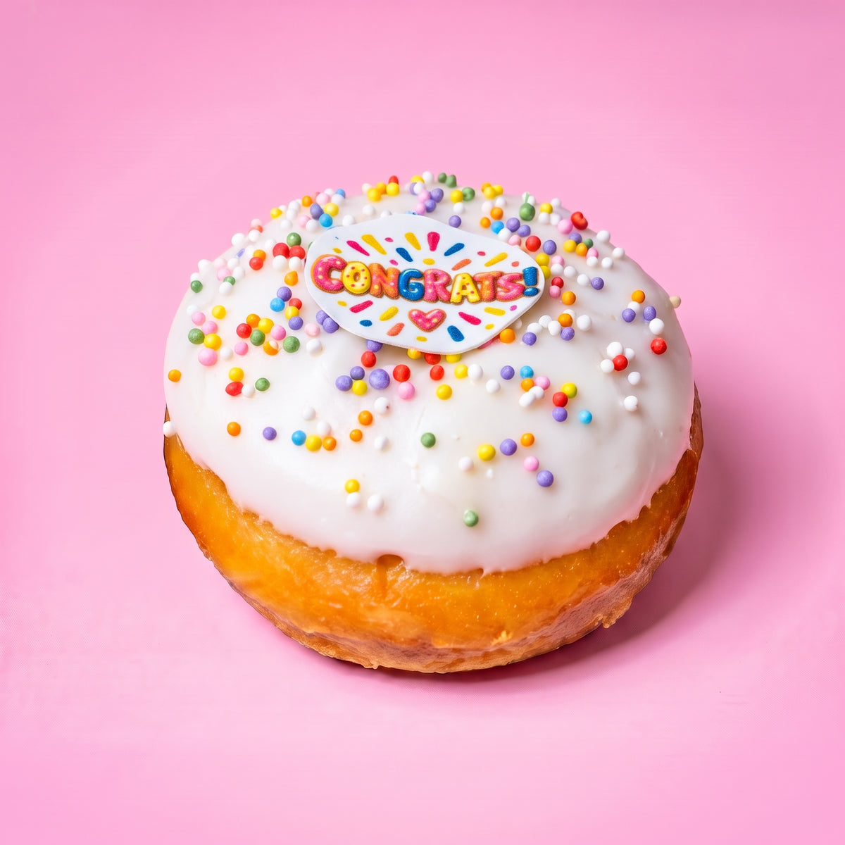 Gluten free vegan celebration doughnut with white icing, rainbow sprinkles and a Congrats topper