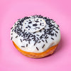 Gluten free vegan football doughnut with white icing, black strand sprinkles and a football topper