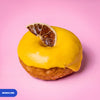 Gluten free vegan fried mango lime doughnut with yellow glaze and a dried lime slice