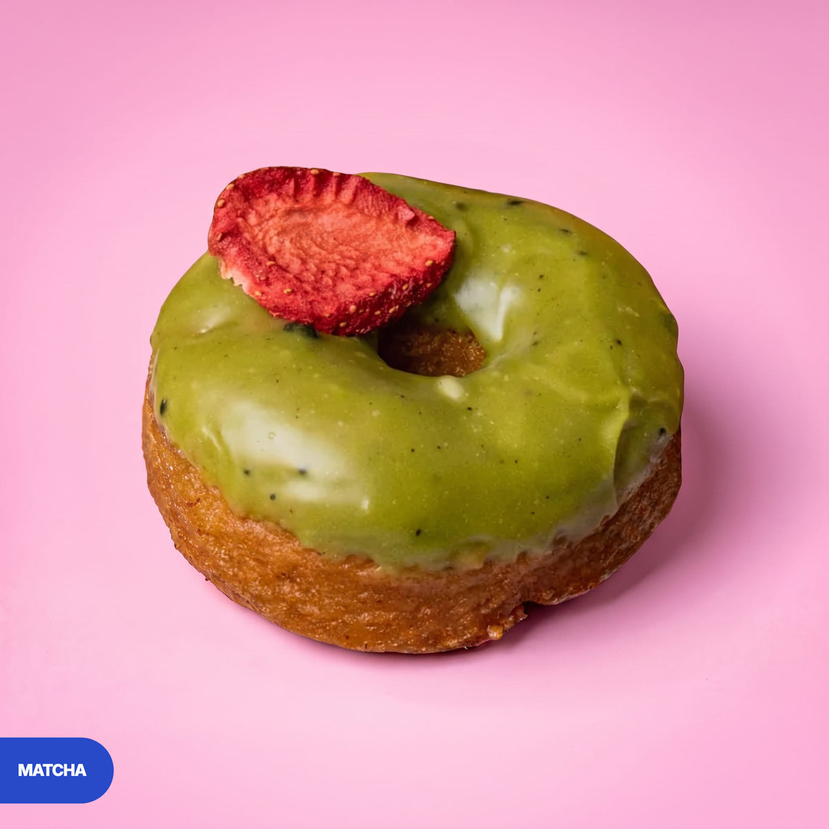 Gluten free vegan fried matcha doughnut with green glaze and a freeze dried strawberry