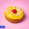 Gluten free vegan fried pina colada doughnut with yellow glaze, toasted coconut flakes and a glace cherry