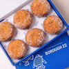 Open Borough 22 box of six gluten free vegan fried sugared doughnuts filled with chocolate cream, the filling visible at the side of each one