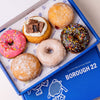 Open Borough 22 box of six gluten free vegan fried doughnuts, pink and chocolate iced rings with sprinkles, cookies and cream, sugared filled rounds and a vanilla glazed ring
