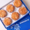 Open Borough 22 box of six gluten free vegan fried sugared doughnuts filled with vanilla custard, the filling visible at the side of each one