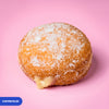 Gluten free vegan fried sugared doughnut filled with vanilla custard, the filling visible at the side
