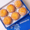 Open Borough 22 box of six gluten free vegan fried sugared doughnuts filled with lemon curd, the filling visible at the side of each one