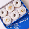 Gluten free vegan doughnuts with white icing, pearl sprinkles and gold heart and champagne toppers in a Borough 22 box
