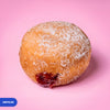 Gluten free oat free vegan fried sugared doughnut filled with raspberry jam, the filling visible at the side