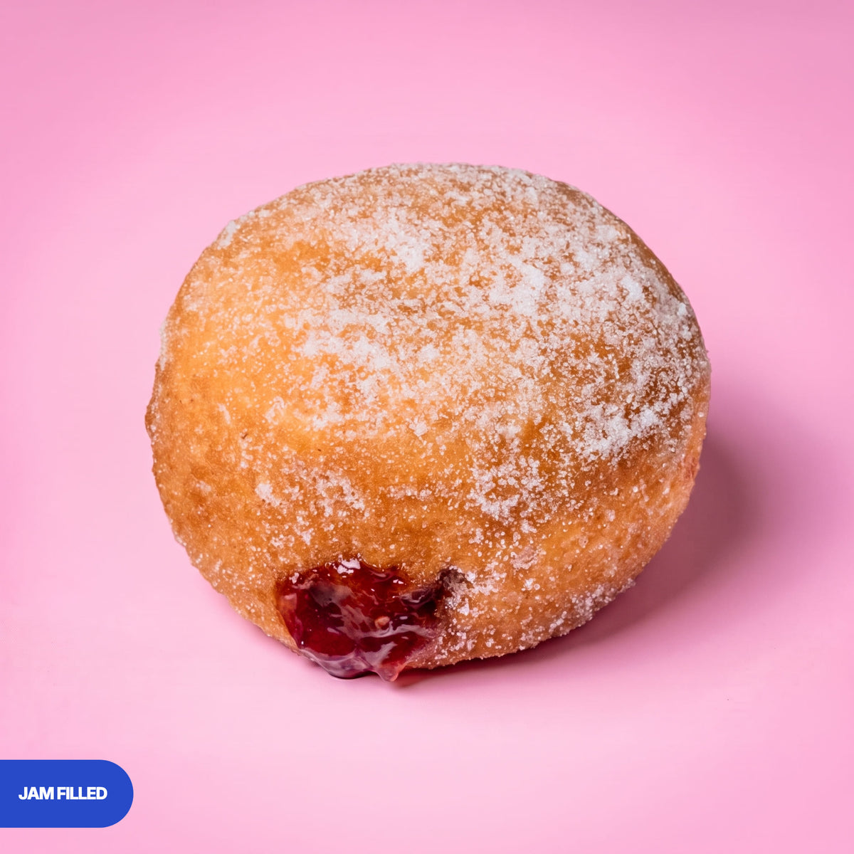 Gluten free oat free vegan fried sugared doughnut filled with raspberry jam, the filling visible at the side