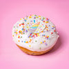 Gluten free vegan unicorn doughnut with white icing, pastel sprinkles and a rainbow unicorn horn topper