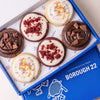 Six gluten free cookies in a blue Borough 22 box: two red velvet with white icing and red crumb, two funfetti with white icing and rainbow sprinkles, and two double chocolate crunch with chocolate icing and chocolate chunks.